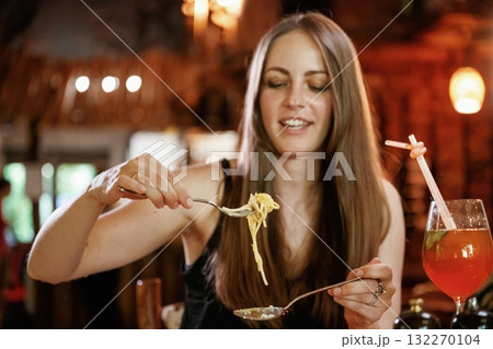 Looking at pasta. Woman is in the restaurant with food and drink 132270104