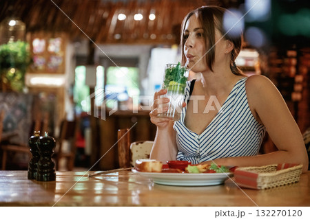 Drinking the mojito. Woman is in the restaurant with food and drink Drinking the mojito. Woman is in the restaurant with food and drink 132270120