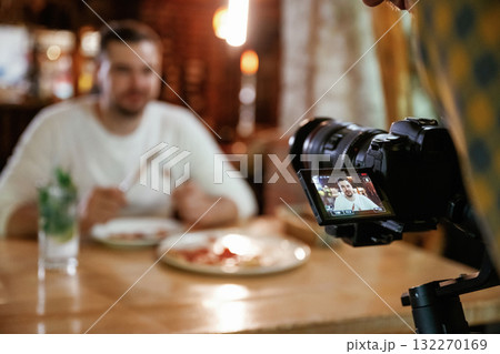 Camera is filming him. Man is sitting in the restaurant and eating a pizza Camera is filming him. Man is sitting in the restaurant and eating a pizza 132270169