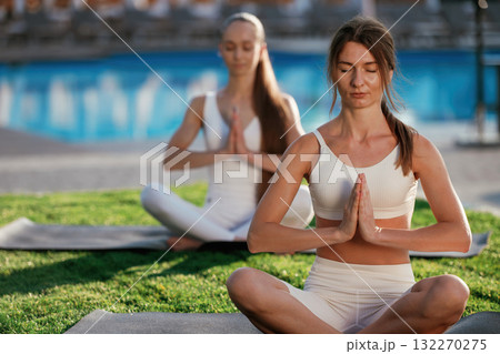 Peaceful meditation practice. Two fitness women are together outdoors, conception of sport 132270275