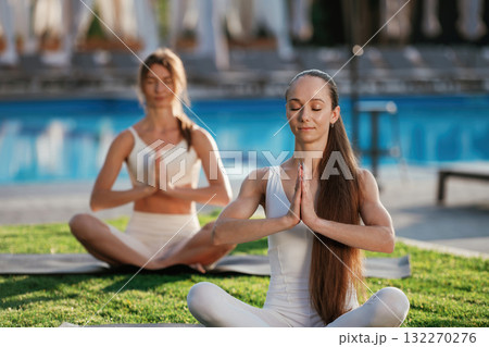 Peaceful meditation practice. Two fitness women are together outdoors, conception of sport Peaceful meditation practice. Two fitness women are together outdoors, conception of sport 132270276