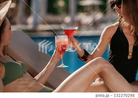 Celebrating, with cocktails. Two beautiful women are resting near the pool Celebrating, with cocktails. Two beautiful women are resting near the pool 132270298