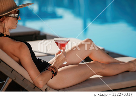 Glass of cocktail in hand. Beautiful young woman is at resort, vacation 132270317