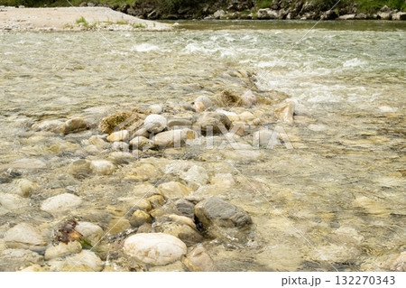 Close-up of a turbulent mountain river with a rocky bottom and shore 132270343