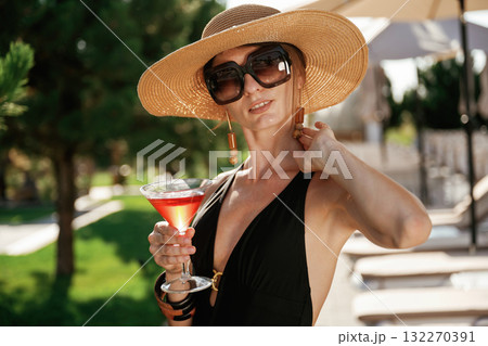 Glass of cocktail in hand. Beautiful young woman is at resort, vacation Glass of cocktail in hand. Beautiful young woman is at resort, vacation 132270391