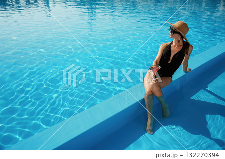 Glass of cocktail in hand. Beautiful young woman is at resort, vacation 132270394