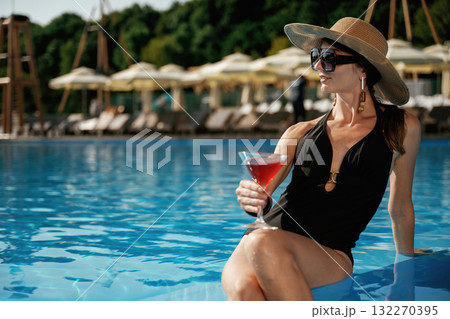 Glass of cocktail in hand. Beautiful young woman is at resort, vacation Glass of cocktail in hand. Beautiful young woman is at resort, vacation 132270395