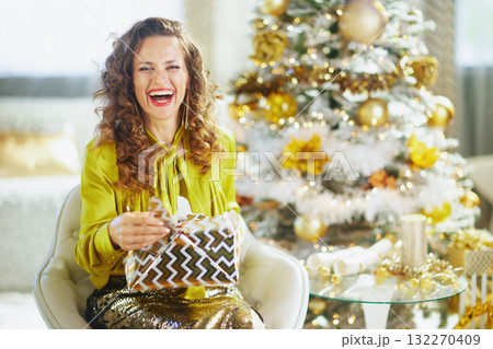 Smiling Woman Unwrapping a Festive Christmas Present Smiling Woman Unwrapping a Festive Christmas Present 132270409