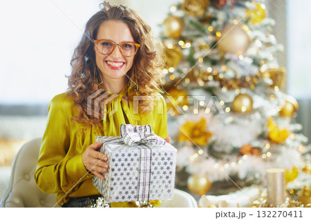 Joyful Woman with Christmas Gift and Flocked Tree 132270411