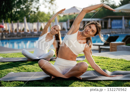 On the yoga mats, doing exercises. Two fitness women are together outdoors, conception of sport 132270562