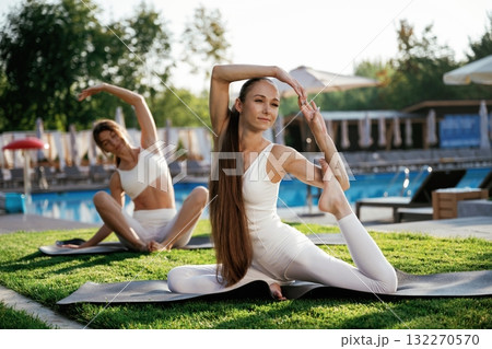 On the yoga mats, doing exercises. Two fitness women are together outdoors, conception of sport 132270570