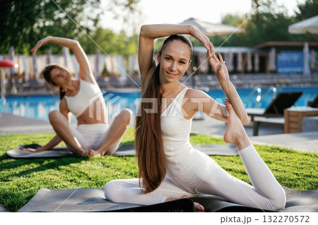 On the yoga mats, doing exercises. Two fitness women are together outdoors, conception of sport 132270572