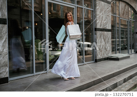 New things, from the sale. Stylish woman is with shopping bag outdoors near the building 132270751