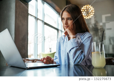 Positive facial expression. Beautiful woman with laptop is in the bar Positive facial expression. Beautiful woman with laptop is in the bar 132270873