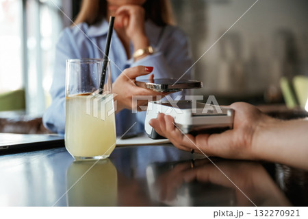 Contactless transfer. Woman is paying for the service in the restaurant 132270921