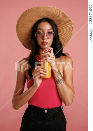 Drinking orange juice. Beautiful young woman is against background Drinking orange juice. Beautiful young woman is against background 132271099