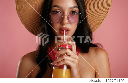 Drinking orange juice. Beautiful young woman is against background Drinking orange juice. Beautiful young woman is against background 132271102