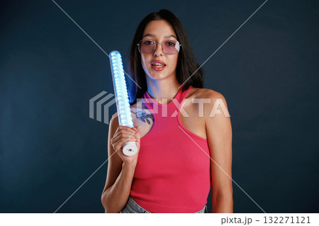 Neon lighting equipment in hands. Beautiful young woman is against background 132271121