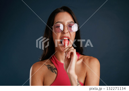 Sweet and tasty lollipop. Beautiful young woman is against background Sweet and tasty lollipop. Beautiful young woman is against background 132271134