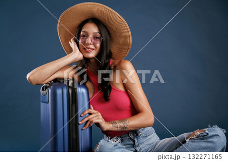 Taking a rest, sitting with suitcase. Beautiful young woman is against background 132271165