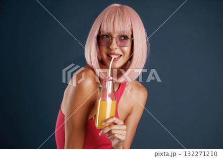 Pink hair, with orange juice. Beautiful young woman is against background Pink hair, with orange juice. Beautiful young woman is against background 132271210