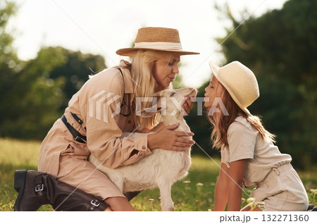 In straw hats. Mother and daughter are together on the farm with goat In straw hats. Mother and daughter are together on the farm with goat 132271360