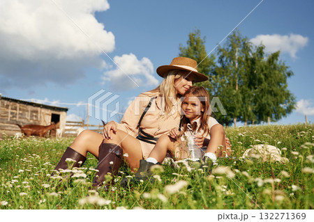 Resting, sitting on the grass. Mother and daughter are together on the farm with goats 132271369