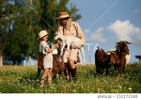 Mother and daughter are together on the farm with goats Mother and daughter are together on the farm with goats 132271388