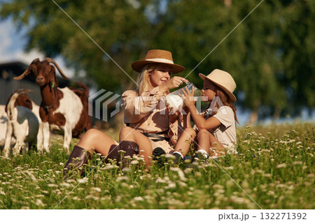 Tasty fresh milk, drinking. Mother and daughter are together on the farm with goats Tasty fresh milk, drinking. Mother and daughter are together on the farm with goats 132271392