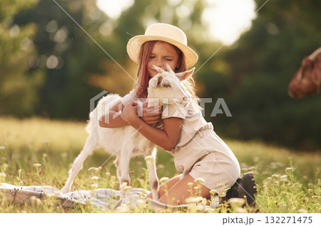 Hugs time. Little girl is on the field with goat 132271475