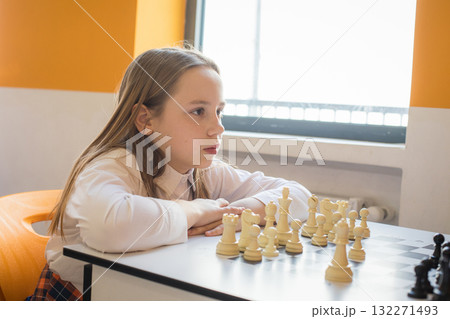 Intelligent child school student on chess lesson indoor. Young girl 10 years old playing chess Intelligent child school student on chess lesson indoor. Young girl 10 years old playing chess 132271493