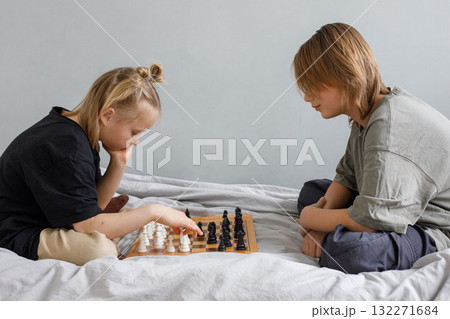 Happy childhood. Two cute children playing chess at home Happy childhood. Two cute children playing chess at home 132271684