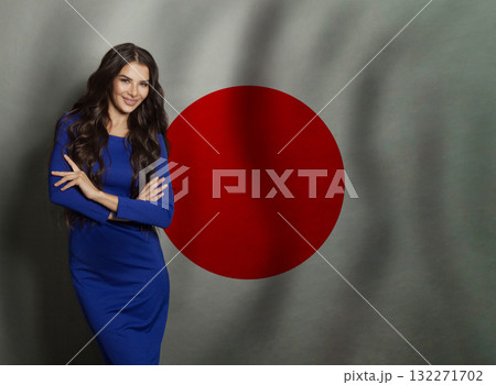Joyful young woman in blue dress smiling against Japanese flag background Joyful young woman in blue dress smiling against Japanese flag background 132271702