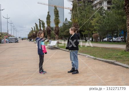 Two young girl children standing on the street and looking at each other 132271770