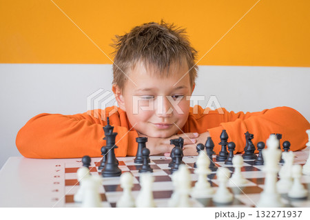 Handsome school boy student playing chess in the classroom. Child with chess indoor 132271937