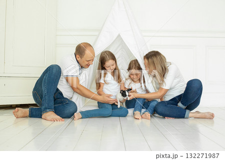 New friend. Happy family and puppy dog pet at home. Father, mother and two daughter 132271987