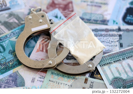 Egyptian pound currency money bills and cocaine pack with handcuffs close up. The concept of drug crimes 132272004