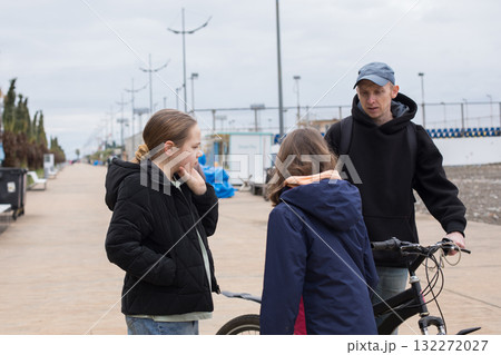 Pretty child girls 10 and 12 years old and her father with bicycle walking outdoors Pretty child girls 10 and 12 years old and her father with bicycle walking outdoors 132272027