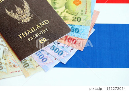 Thai baht currency money bills and passport lies on flag close up. The concept of travel and vacation Thai baht currency money bills and passport lies on flag close up. The concept of travel and vacation 132272034