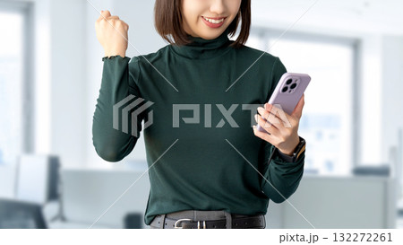 スマートフォンを見て喜ぶ笑顔の女性・ビジネスウーマン スマートフォンを見て喜ぶ笑顔の女性・ビジネスウーマン 132272261