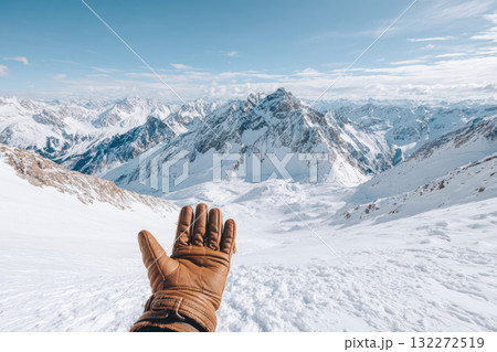 Hand wearing brown glove reaching out over snowy mountain ridge clear blue sky winter landscape adventure serene cold outdoor exploration scenic view travel inspiration Hand wearing brown glove reaching out over snowy mountain ridge clear blue sky winter landscape adventure serene cold outdoor exploration scenic view travel inspiration 132272519