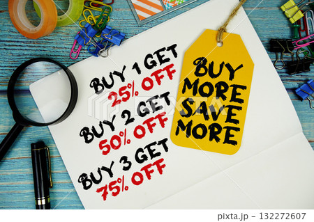 Buy 1 get 25%, Buy 2 get 50%, Buy 3 get 75% text on a notepad paper and Buy More Save More with price tag surrounded by office supplies and magnifying glass on a blue wooden surface Buy 1 get 25%, Buy 2 get 50%, Buy 3 get 75% text on a notepad paper and Buy More Save More with price tag surrounded by office supplies and magnifying glass on a blue wooden surface 132272607