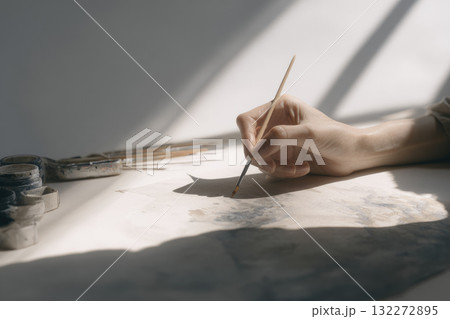 Hand painting with watercolor on paper soft natural light neutral tones creative process artistic expression close up calm atmosphere art supplies brush peaceful mood Hand painting with watercolor on paper soft natural light neutral tones creative process artistic expression close up calm atmosphere art supplies brush peaceful mood 132272895