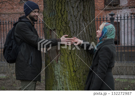 Cheerful man and woman holding each others hands outdoors in park Cheerful man and woman holding each others hands outdoors in park 132272987