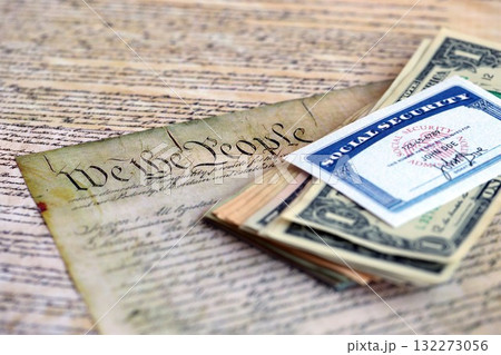 Social Security Cards Symbolizing Benefits for Elderly United States citizens and taxpayers. SSN card with money on US Constitution close up Social Security Cards Symbolizing Benefits for Elderly United States citizens and taxpayers. SSN card with money on US Constitution close up 132273056