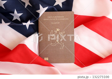 Luxembourg passport on big waving flag of United States of America close up. US Visa and immigration concept 132273100
