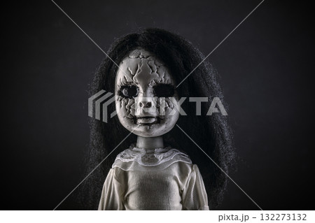 Portrait of a scary cracked doll with black hair on dark background 132273132