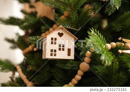 A charming wooden miniature house ornament hangs on a Christmas tree A charming wooden miniature house ornament hangs on a Christmas tree 132273181