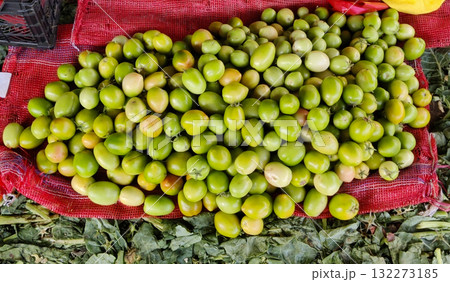 A generous mound of unripe green olives displayed on a red mesh cloth suggesting a bountiful harvest and fresh produce A generous mound of unripe green olives displayed on a red mesh cloth suggesting a bountiful harvest and fresh produce 132273185