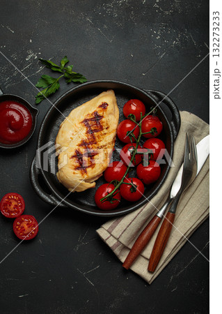 Grilled chicken breast fillet with cherry tomatoes in cast iron pan and tomato sauce top view on rustic black background, healthy food Grilled chicken breast fillet with cherry tomatoes in cast iron pan and tomato sauce top view on rustic black background, healthy food 132273233